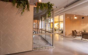 Moderne kantoorruimte op Luttenbergweg 8 in Amsterdam Zuid-Oost met glazen wanden en planten. Ideaal voor bedrijven die een ruim en stijlvol kantoorpand willen huren.