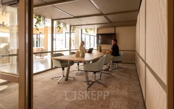 Moderne kantoorruimte aan de Luttenbergweg 8 in Amsterdam Zuid-Oost met glazen wanden en een grote vergadertafel, ideaal voor zakelijke ontmoetingen en kantoorruimte huren.