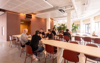 Moderne kantoorruimte aan Luttenbergweg 8, Amsterdam Zuid-Oost met mensen aan tafels in bespreking, te huur voor flexibele werkplekken.