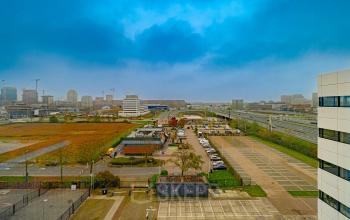 Uitzicht op de Luttenbergweg 8 in Amsterdam Zuid-Oost, met omliggende kantoorpanden en parkeerplaatsen. Ideale locatie voor wie kantoorruimte huren wil in een zakelijke omgeving.
