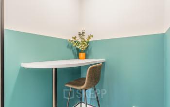 Gezellige hoek van een kantoorpand aan de Paasheuvelweg 20 in Amsterdam Zuid-Oost met een hoge tafel en stoel, ideaal voor informeel werken of pauzes. Perfect voor kantoorruimte huren.