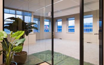 Ongemeubileerd kantoor in Amsterdam Zuid-Oost met moderne glazen deur. Ideaal om kantoorruimte te huren met uitzicht op gebouwen, veel licht en planten voor een frisse uitstraling.