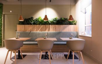 Een modern ingerichte werkruimte in een kantoorpand op Hullenbergweg 109-135, Amsterdam Zuid-Oost, met stijlvolle stoelen en tafels, omgeven door groene planten. Ideaal voor kantoorruimte huren.