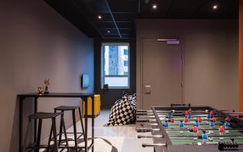 Speelse kantoorruimte te huur op Hullenbergweg 109-135 in Amsterdam Zuid-Oost, met een tafelvoetbaltafel en zitgedeelte. Ideaal voor ontspannen pauzes tussen het werken door.