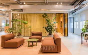 Moderne kantoorruimte in Amsterdam Zuid-Oost met stijlvolle zitbanken en groene planten, ideaal om te huren voor creatieve brainstormsessies.