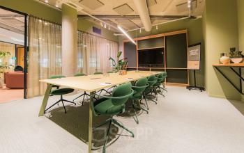 Moderne vergaderruimte in een kantoorpand aan de Hullenbergweg 109-135, Amsterdam Zuid-Oost, met een grote tafel en groene stoelen, ideaal voor kantoorruimte huren.
