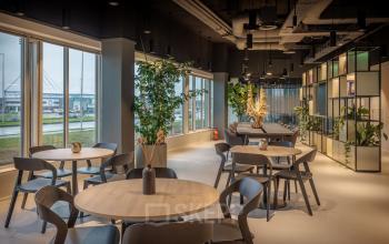 Moderne en licht ingerichte kantoorruimte aan de Herikerbergweg 290 in Amsterdam Zuid-Oost, met ronde tafels en een groene inrichting. Geschikt voor huur en flexibele werkplekken.