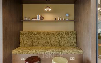 Moderne zitruimte met ingebouwde bank en decoratieve items, ideaal voor informeel overleg in een kantoorpand op Herikerbergweg 290, geschikt om kantoorruimte te huren in Amsterdam Zuid-Oost.