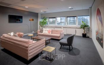 Comfortabele lounge met moderne banken, stoelen en planten in het kantoorpand aan Hogehilweg 8, Amsterdam Zuid-Oost.
