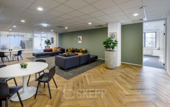 Kantoorpand op Karspeldreef 8 in Amsterdam Zuid-Oost, moderne werkruimte met zithoeken en vergadertafel, met houten vloer en planten voor een huiselijke sfeer.