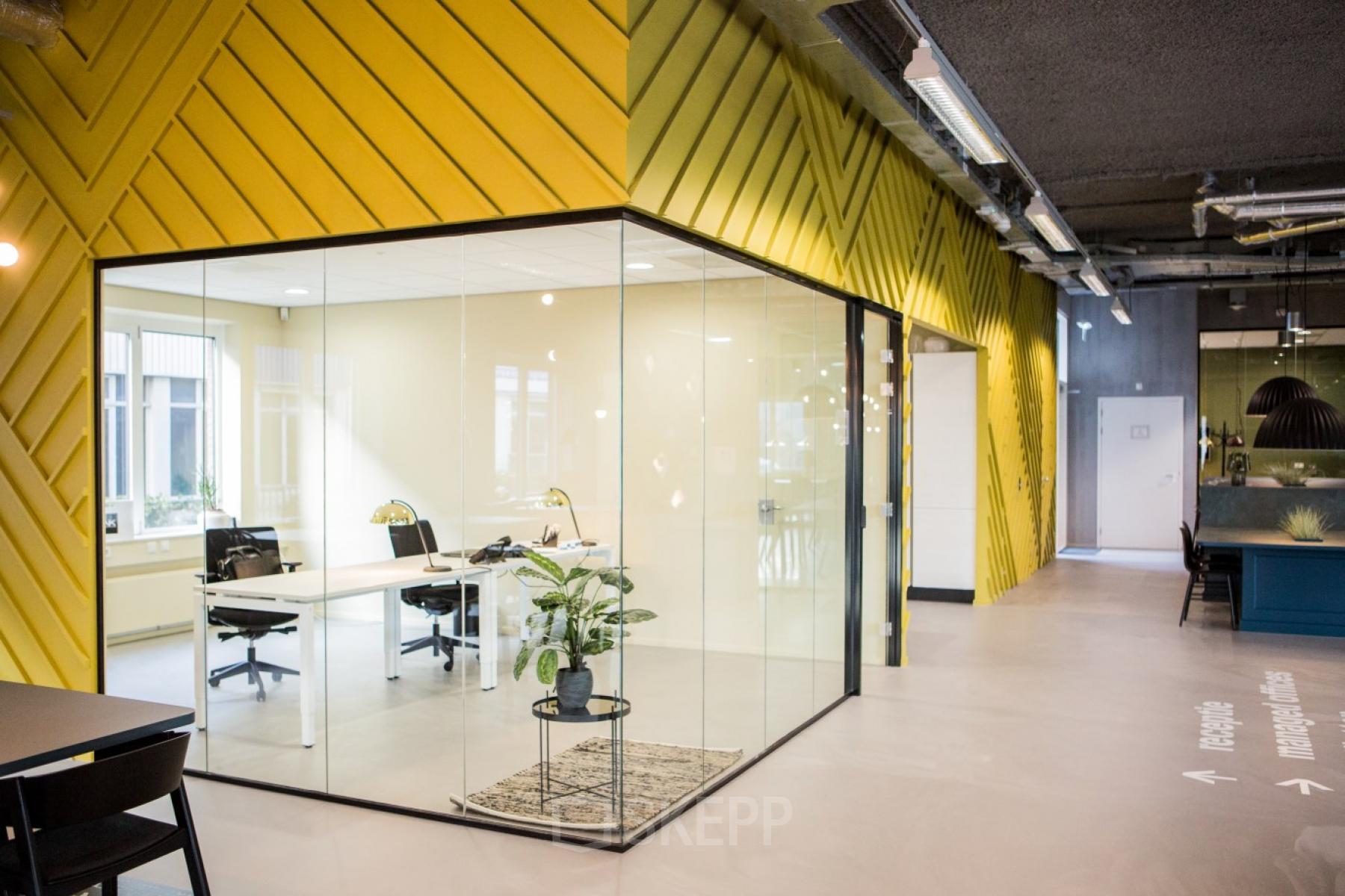 Moderne kantoorruimte huren aan de Burgemeester Stramanweg 102 in Amsterdam Zuid-Oost met glazen wanden, gele accenten en voorzien van comfortabele werkplekken.