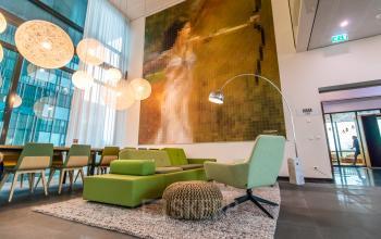 Modern ingerichte kantoorruimte aan de Herikerbergweg 292 in Amsterdam Zuid-Oost met groene meubels en artistieke wanddecoratie. Perfect voor kantoorruimte huren met aantrekkelijke faciliteiten.