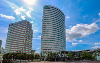 Modern kantoorpand op De Entree 99-197 in Amsterdam Zuid-Oost met indrukwekkende gevel en glaswerk. Ideaal voor kantoorruimte huren. Blauw lucht complimenteert het ontwerp van de moderne kantoren.