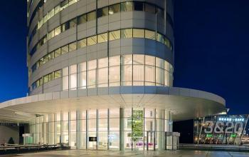 Modern kantoorpand gelegen aan De Entree 99-197 in Amsterdam Zuid-Oost, met glazen gevel en verlichte ingang.