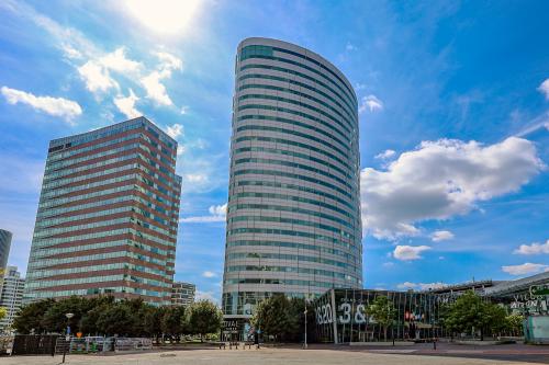 Modern kantoorpand op De Entree 99-197 in Amsterdam Zuid-Oost met indrukwekkende gevel en glaswerk. Ideaal voor kantoorruimte huren. Blauw lucht complimenteert het ontwerp van de moderne kantoren.