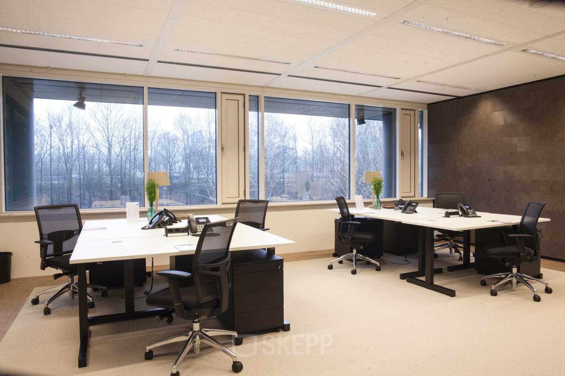 Kantoorruimte huren in Amsterdam-Zuid-Oost op De Entree 99-197, met grote ramen en diverse werkplekken met bureaus en stoelen.