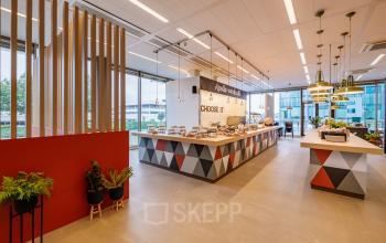 Kantoorruimte huren aan de Herikerbergweg 1-35 in Amsterdam Zuid-Oost, moderne en gemeubileerde pantry met planten, grote ramen en eetruimte.