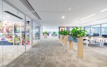 Kantoorruimte huren op Herikerbergweg 1-35 in Amsterdam Zuid-Oost, moderne inrichting met glazen wanden en veel groen.