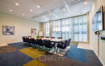 Vergaderruimte in het kantoorpand op Herikerbergweg 1-35, Amsterdam Zuid-Oost, met grote tafel, stoelen en presentatiefaciliteiten, geschikt voor zakelijke bijeenkomsten.