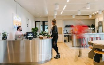 Moderne kantoorruimte huren op Strawinskylaan 4117, Amsterdam Zuidas met een receptie en personeelsruimte. Twee mensen voeren zakelijke activiteiten uit.