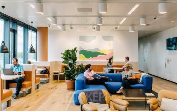 Moderne kantoorruimte huren aan Strawinskylaan 4117, Amsterdam Zuidas. Mensen werken en ontspannen op kleurrijke meubels in open werkgebied met veel licht.