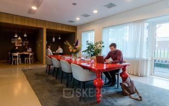 Moderne kantoorruimte huren op de Barbara Strozzilaan 101-201 in Amsterdam Zuidas, met royale vergadertafel en zakelijke activiteiten.