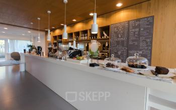 Moderne pantry in kantoorpand op Barbara Strozzilaan 101-201, Amsterdam Zuidas, met een lange toonbank en diverse lekkernijen, ideaal voor een kantoorruimte huren.