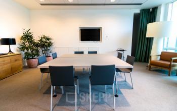 Moderne kantoorruimte op Barbara Strozzilaan 101-201, Amsterdam Zuidas, met vergadertafel, stoelen en een televisie aan de muur. Ideaal voor wie kantoorruimte wil huren in een stijlvol kantoorpand.