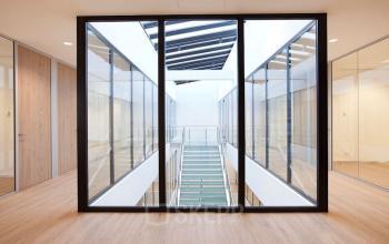 Ruime kantoorruimte met glazen wanden aan De Boelelaan 30, Amsterdam Zuidas. De ruimte heeft een moderne uitstraling met houten vloeren en veel natuurlijk licht.
