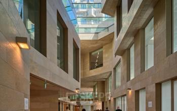 Binnenplaats met moderne architectuur in het kantoorpand Beethovenstraat 503, Amsterdam Zuidas. Drie personen bezig met kantooractiviteiten. Ideale locatie voor kantoorruimte huren.