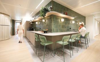 Moderne kantoorruimte huren aan Beethovenstraat 503 in Amsterdam Zuidas met een gemeubileerde kantoorpantry waar mensen zakelijke activiteiten uitvoeren.