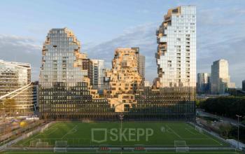 Exterieur van het kantoorpand Beethovenstraat 503 in Amsterdam Zuidas, modern ontwerp met glazen gevels. Kantoorruimte huren in een dynamische omgeving met uitzicht op een voetbalveld.