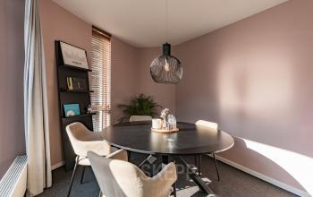 Vergaderruimte te huur in kantoorpand op de Boelelaan 1110, Amsterdam Zuidas. De ruimte is gemeubileerd met een ovale tafel en stoelen, omringd door lichtroze muren en een hanglamp.