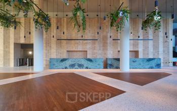Modern ingerichte entree in een kantoorpand op Hildegard Von Bingenstraat 44, Amsterdam Zuidas, met natuurlijke elementen en strakke lijnen. Ideaal voor bedrijven die kantoorruimte willen huren op een toplocatie.