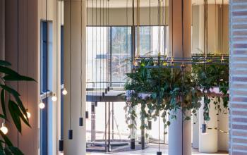Ruime, lichte entree van kantoorpand op Hildegard Von Bingenstraat 44 in Amsterdam Zuidas, met moderne hanglampen en groene accenten. Ideaal voor wie een kantoorruimte wil huren.