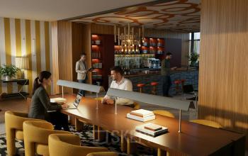 Gezellige kantoorkamer in Amsterdam Zuidas op Barbara Strozzilaan 101 101, met een moderne inrichting en medewerkers bezig met overleg en werkzaamheden aan een grote tafel nabij de stijlvolle bar.