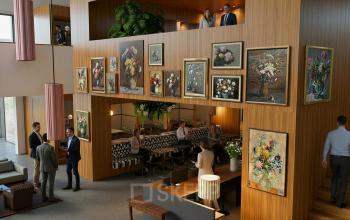 Modern kantoorpand aan de Amsterdam Zuidas met kunstsfeer. Mensen voeren zakelijke gesprekken in het gemeubileerde interieur. Perfecte plek voor kantoorruimte huren.