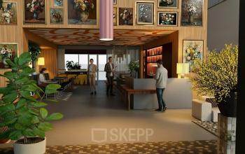 Moderne en stijlvolle kantoorruimte in Amsterdam Zuidas met kleurrijke kunst aan de muren, planten en een uitnodigende ontvangstbalie. Personen zijn bezig met zakelijke gesprekken en werkzaamheden.