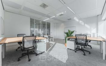 Moderne kantoorruimte te huur op Barbara Strozzilaan 101, Amsterdam Zuidas, met strakke bureaus, bureaustoelen en veel natuurlijk licht door grote ramen.