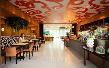 Moderne kantoorruimte op Barbara Strozzilaan 101, Amsterdam Zuidas, met kleurrijk interieur, stijlvolle zitplaatsen en een bar. Twee mensen werken op laptops in een ontspannen setting.
