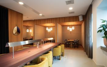 Moderne kantoorruimte met houten tafel en gele stoelen op Barbara Strozzilaan 101, Amsterdam Zuidas, geschikt voor werk of vergaderingen. Verfijnd interieur met decoratieve elementen en sfeerverlichting.