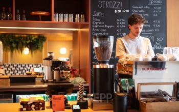 Een barista bereidt koffie in een modern ingerichte koffiehoek in een kantoorpand aan de Barbara Strozzilaan 101 in Amsterdam Zuidas.