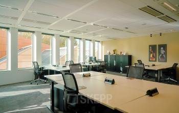 Kantoorruimte huren aan de Jachthavenweg 109 in Amsterdam Zuidas, met een open indeling, bureaus en stoelen, veel natuurlijk licht en wanddecoraties.