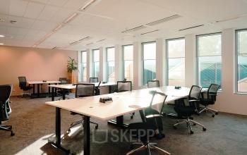 Ruime en lichte kantoorruimte met grote ramen en moderne meubels aan Jachthavenweg 109, Amsterdam Zuidas, met meerdere bureaus en stoelen.