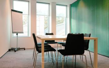Vergaderruimte in een kantoorpand aan de Jachthavenweg 109, Amsterdam Zuidas, met grote ramen, een tafel en stoelen met zicht op groen. Ideaal voor wie kantoorruimte wil huren.