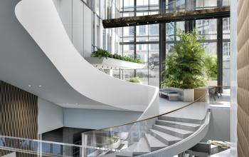 Moderne open kantoorruimte op de Claude Debussylaan 80-134 in Amsterdam Zuidas met veel natuurlijk licht, glazen balustrades en groene planten. Perfect voor kantoorruimte huren in een stijlvol kantoorpand.