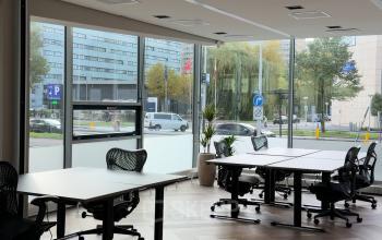 Lichte kantoorruimte aan de De Boelelaan 28 in Amsterdam Zuidas, met moderne bureaus en stoelen tegen een achtergrond van grote ramen met uitzicht op de straat.