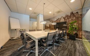 Vergaderruimte van het kantoorpand op Claude Debussylaan 10, Amsterdam Zuidas met stoelen, tafel en een groot scherm.