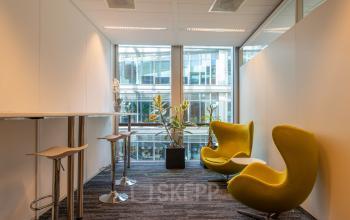 Moderne kantoorruimte huren met groene stoelen en hoge tafels gelegen op Claude Debussylaan 10, Amsterdam Zuidas.