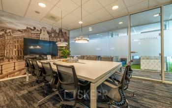 Vergaderruimte in kantoorpand aan Claude Debussylaan 10, Amsterdam Zuidas, met moderne meubels en zicht op glazen wanden.